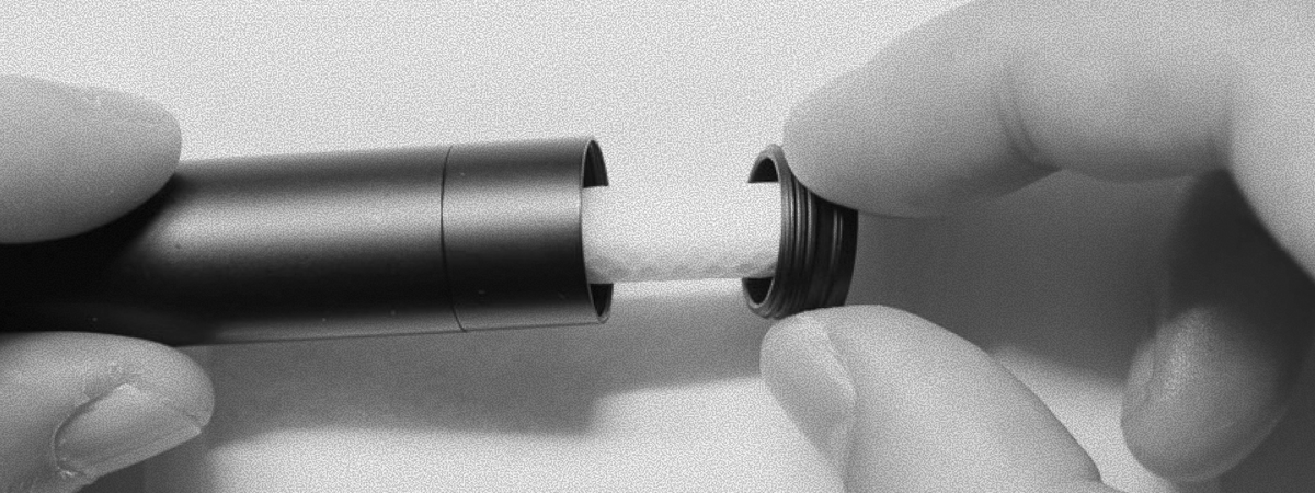 Hands pulling the cotton wick out of an aluminium nasal inhaler