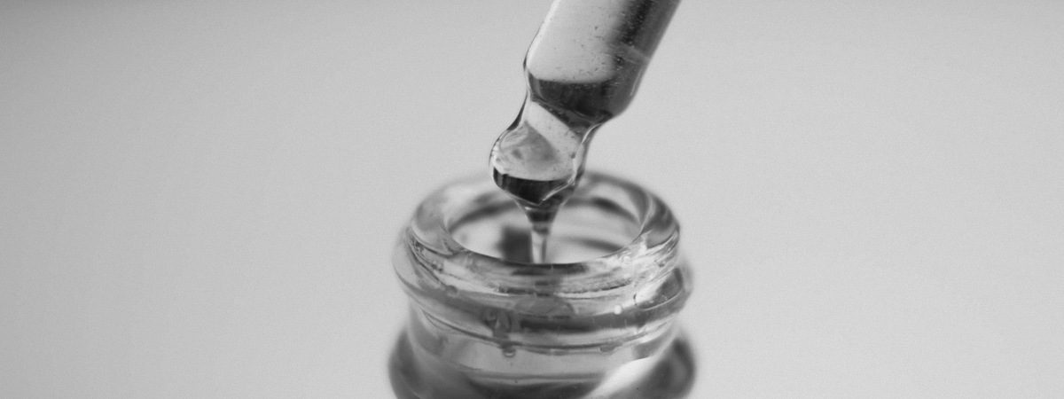 Close-up of a glass dropper dispensing essential oil into a bottle