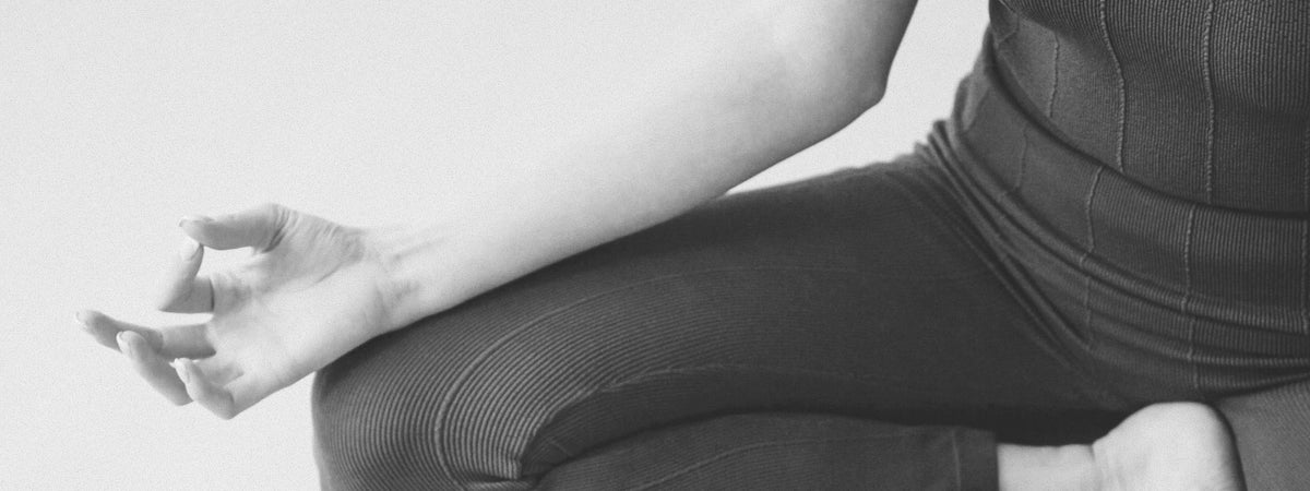 A person's arm resting with the hand loosely open in a meditation pose, black and white
